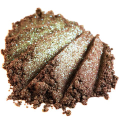 Close-up of duochrome eyeshadow pan shifting from green to brown with iridescent shimmer