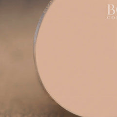 Side view of matte soft pink and beige eyeshadow pan showing smooth pressed powder texture in circular compact