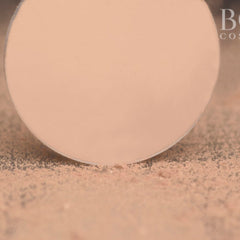 Close-up of fingertips applying soft pink matte eyeshadow to eyelid with gentle blending motion