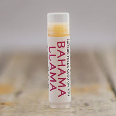 Lip balm tube with white label, pink text, and clear cap, "BAHAMA LLAMA" brand