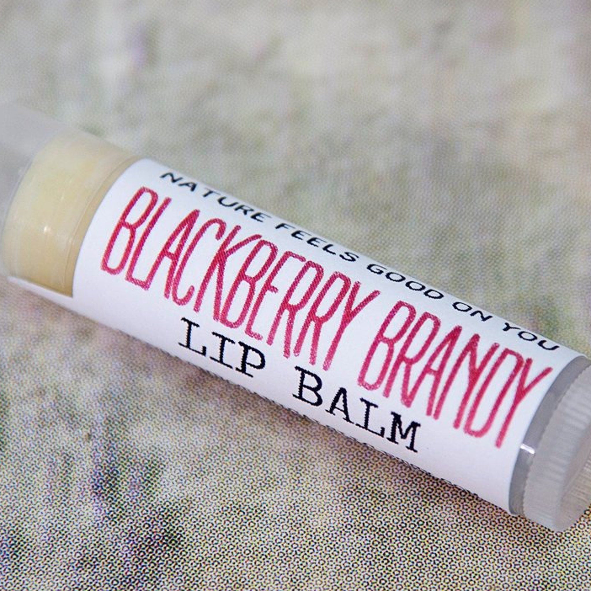 Lip balm tube with white label, red text, and clear plastic cap, Redbarn Botanicals brand