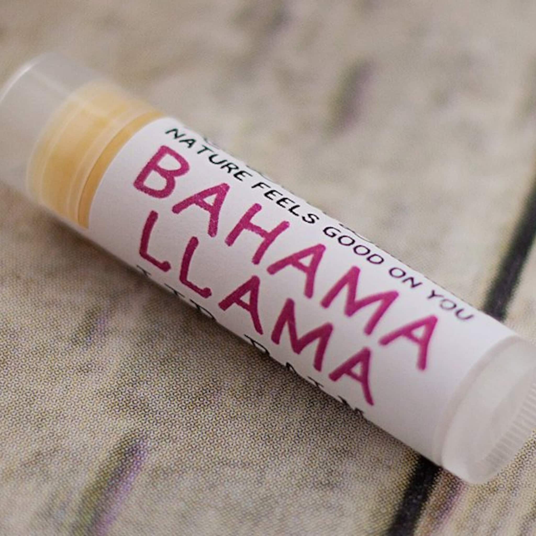 Lip balm tube with white label, pink text "Bahama Llama", and clear cap on a patterned surface