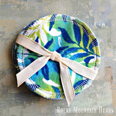 Reusable facial rounds with blue and green floral pattern, white stitched edge, tied with ribbon, Rocky Mountain Herbs text