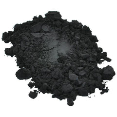 Side view of black iron oxide pigment powder jar with measuring scoop on marble surface