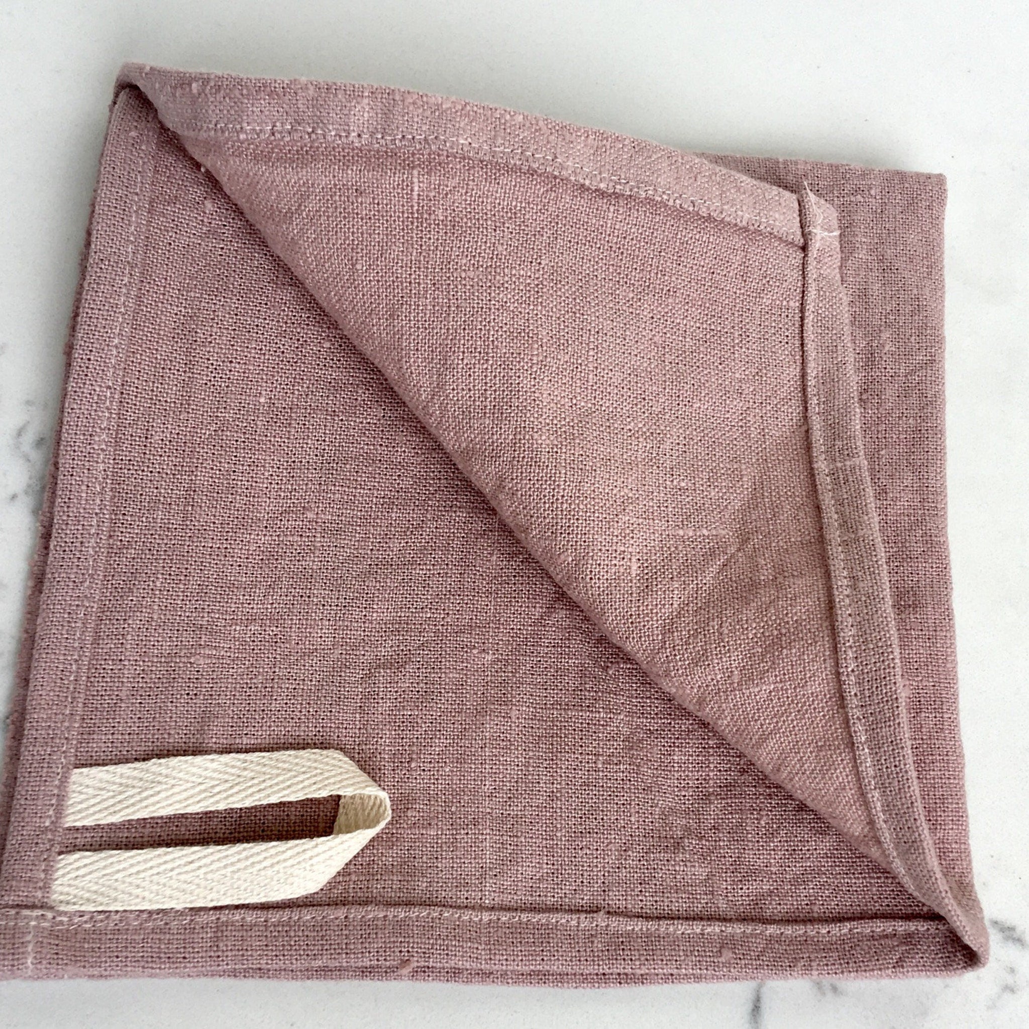 Linen towel in dusty rose color with folded style and hanging loop detail