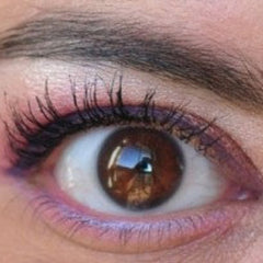 Eye with brown iris, black lashes, and pink eyeshadow around the eye