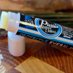 Eye balm tube with white, black, and blue label, yellow balm visible, "Pickles" brand text