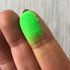 Fingerprints with bright green pigment on skin, showing fingerprint detail and texture