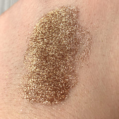 Hand applying Tala Cafe au Lait glitter eye shadow pigment with fingertip, showing shimmering taupe-brown texture