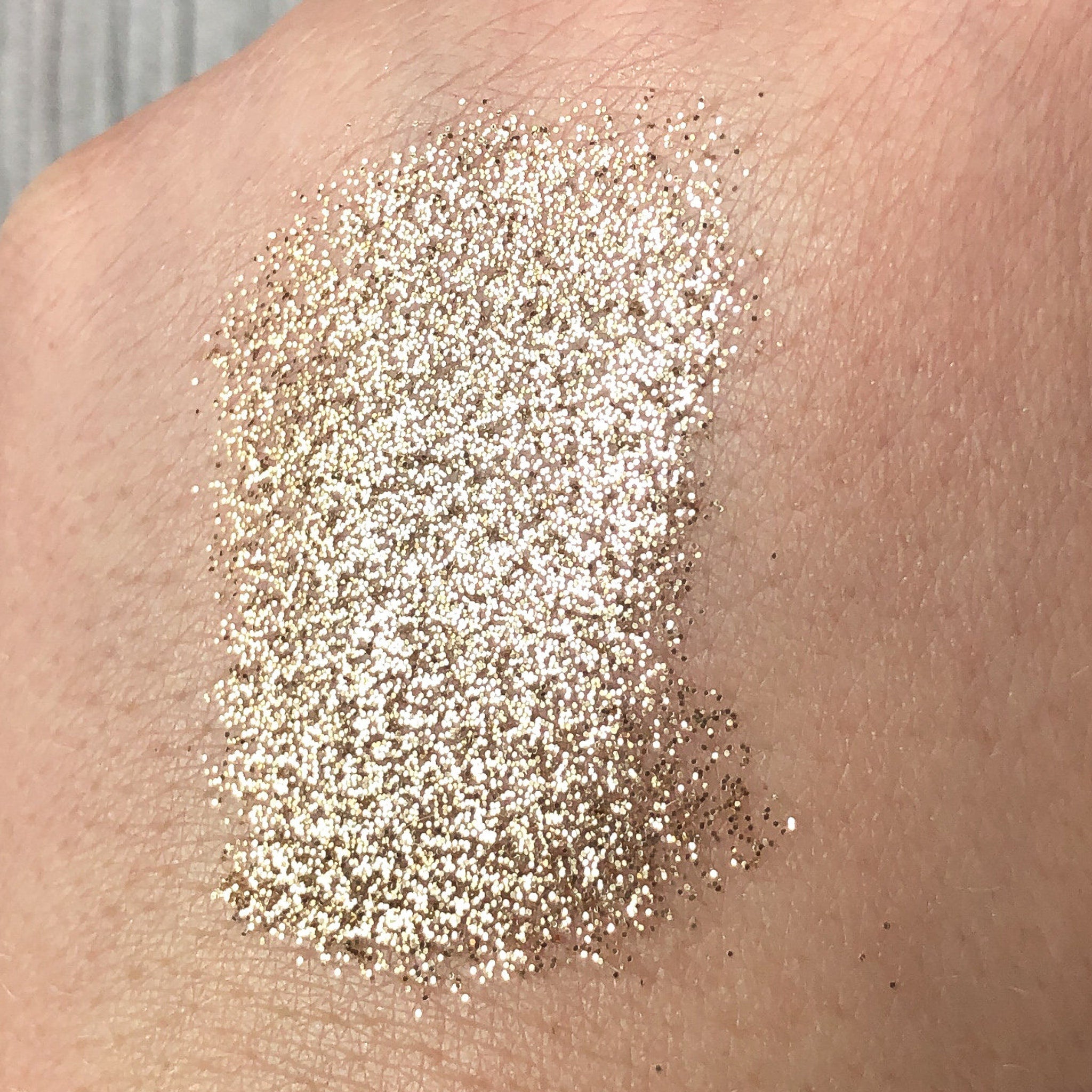 Close-up of Tala Golden Halo glitter eye shadow pigment showing intense metallic gold shimmer in textured finish