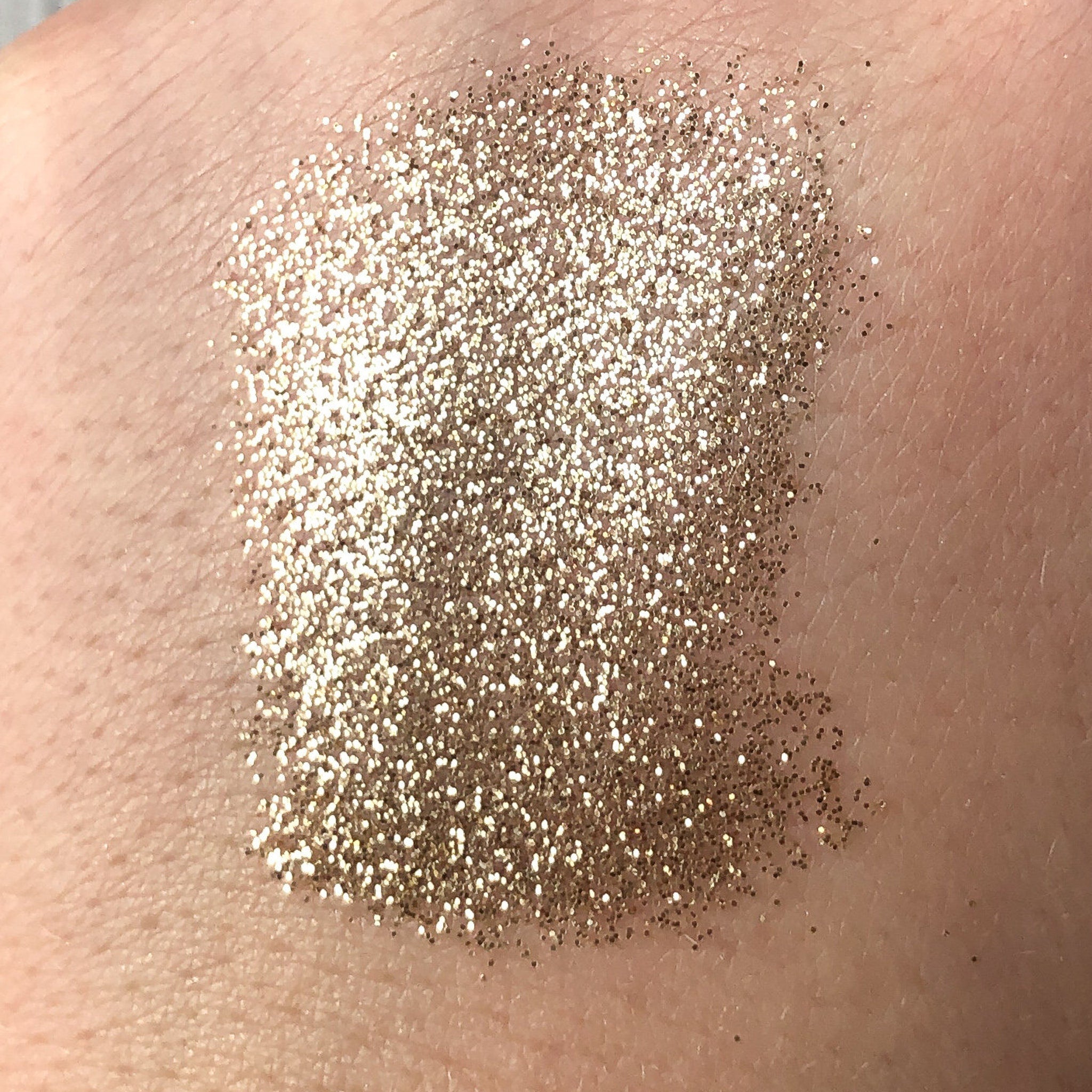 Side view of Tala Golden Halo glitter eye shadow pigment in 2ml tube showcasing metallic gold shimmer texture