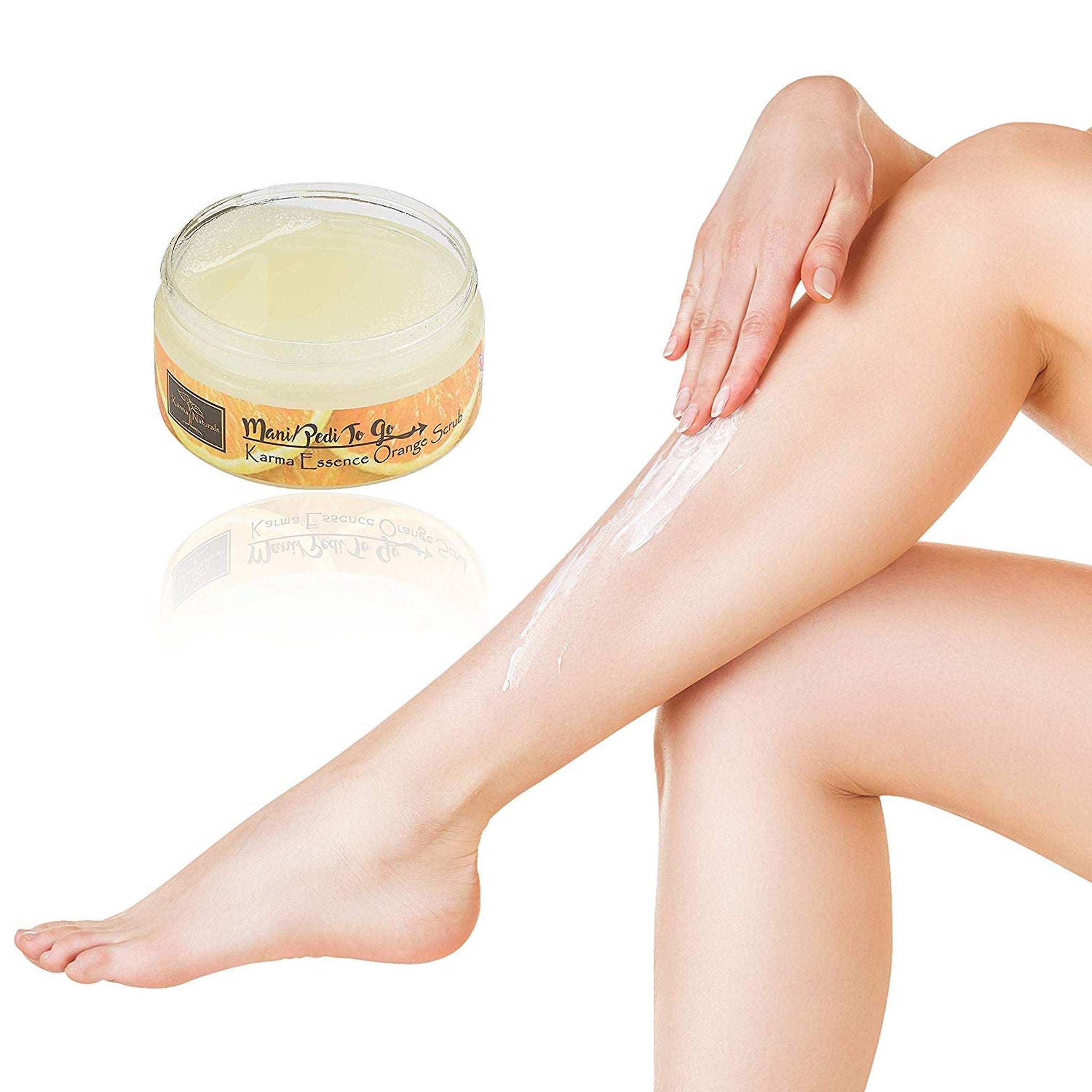 Orange scrub jar with yellow gel, white cream being applied to leg, Karma Essence label visible