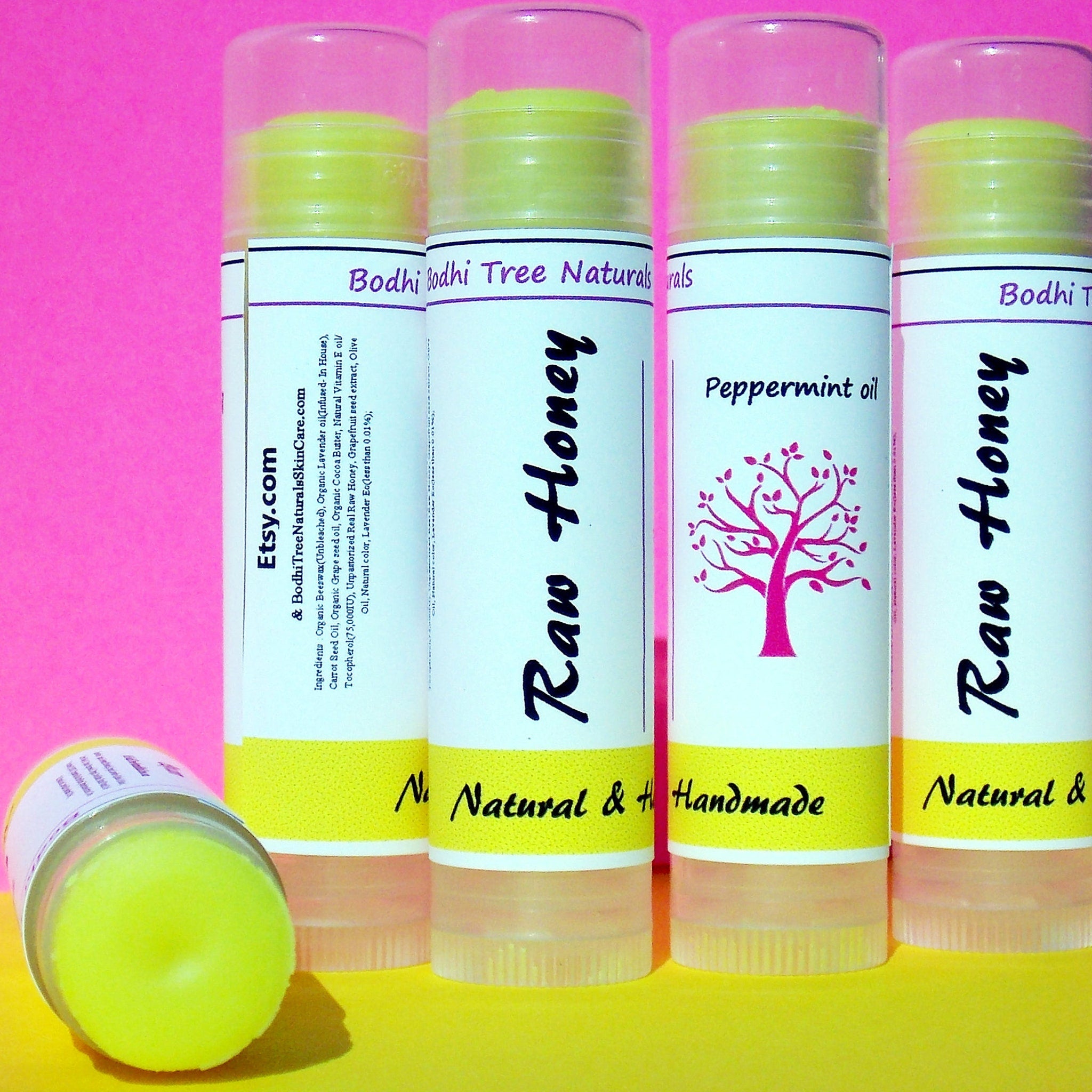 Lip balm tubes with yellow balm, white labels, and Bodhi Tree Naturals text, on yellow surface