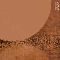 Side view of golden brown matte eyeshadow pan showing pressed powder texture and circular shape