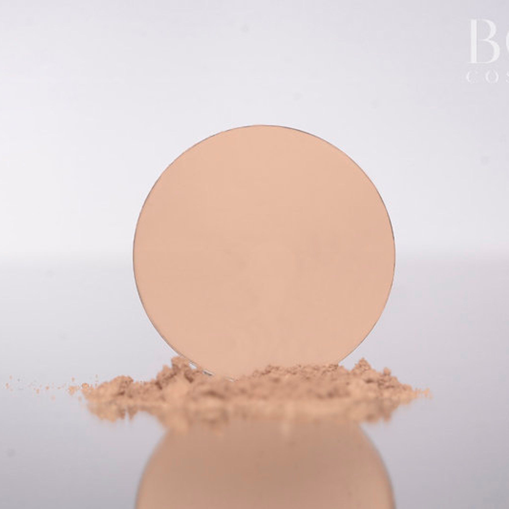 Close-up of matte soft pink and beige eyeshadow in a round 37mm pan with smooth pressed powder texture