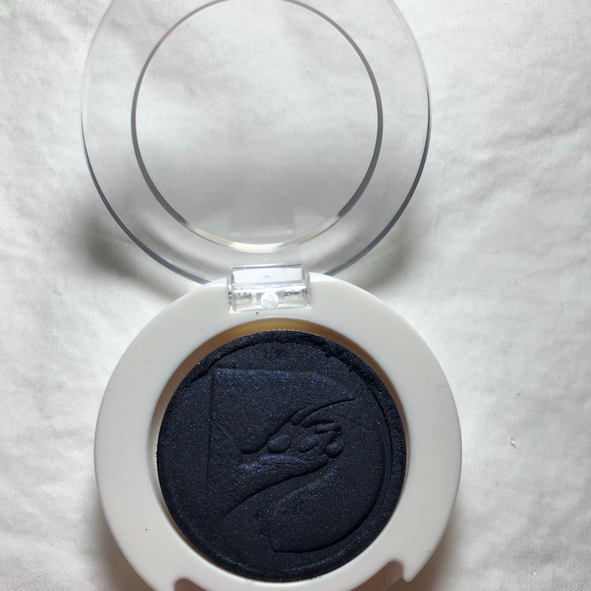 Side view of round 26mm pressed mineral eyeshadow by Jack showing smooth texture and rich pigment in compact