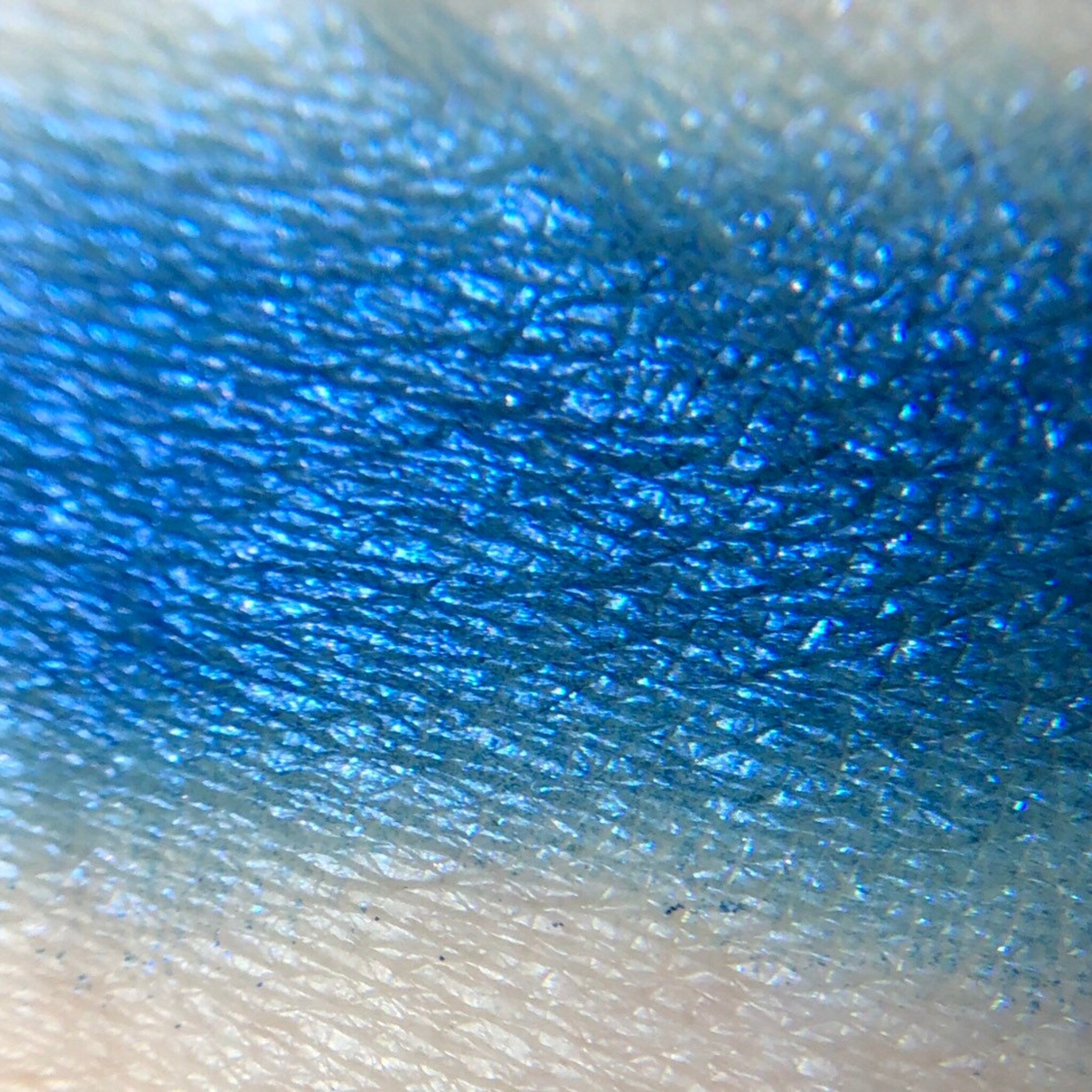 Close-up of fingertips applying pressed mineral eye shadow in a circular motion to eyelid