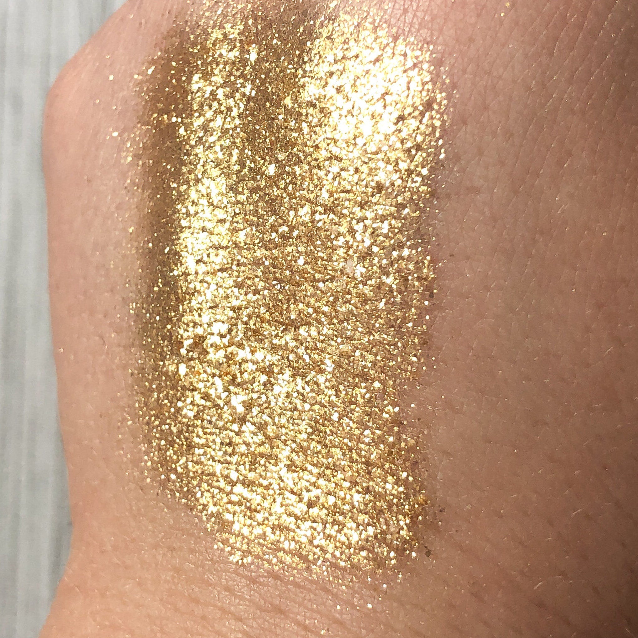 Gold glitter on skin, showing texture and shimmer, applied to arm