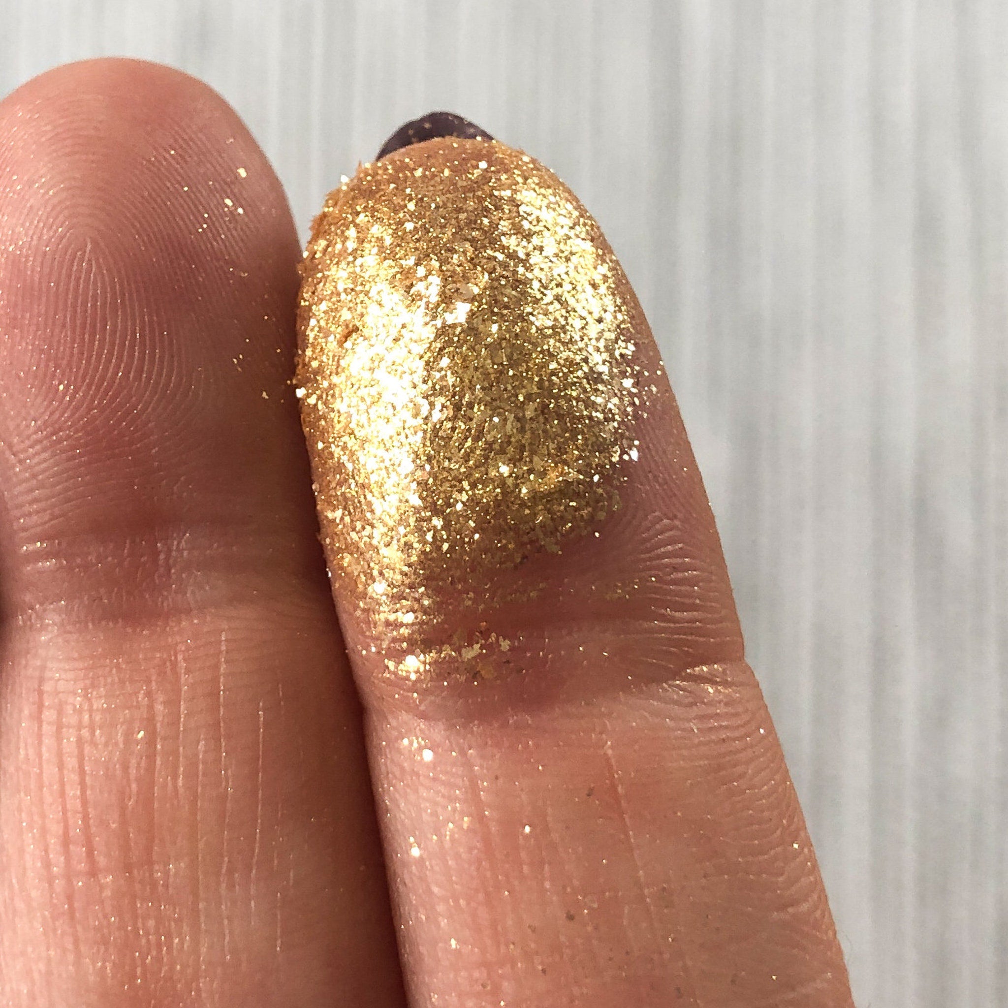 Gold glitter on finger, showing texture and color against skin