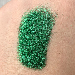 Green glitter eyeshadow swatch on skin, showing sparkle and texture detail