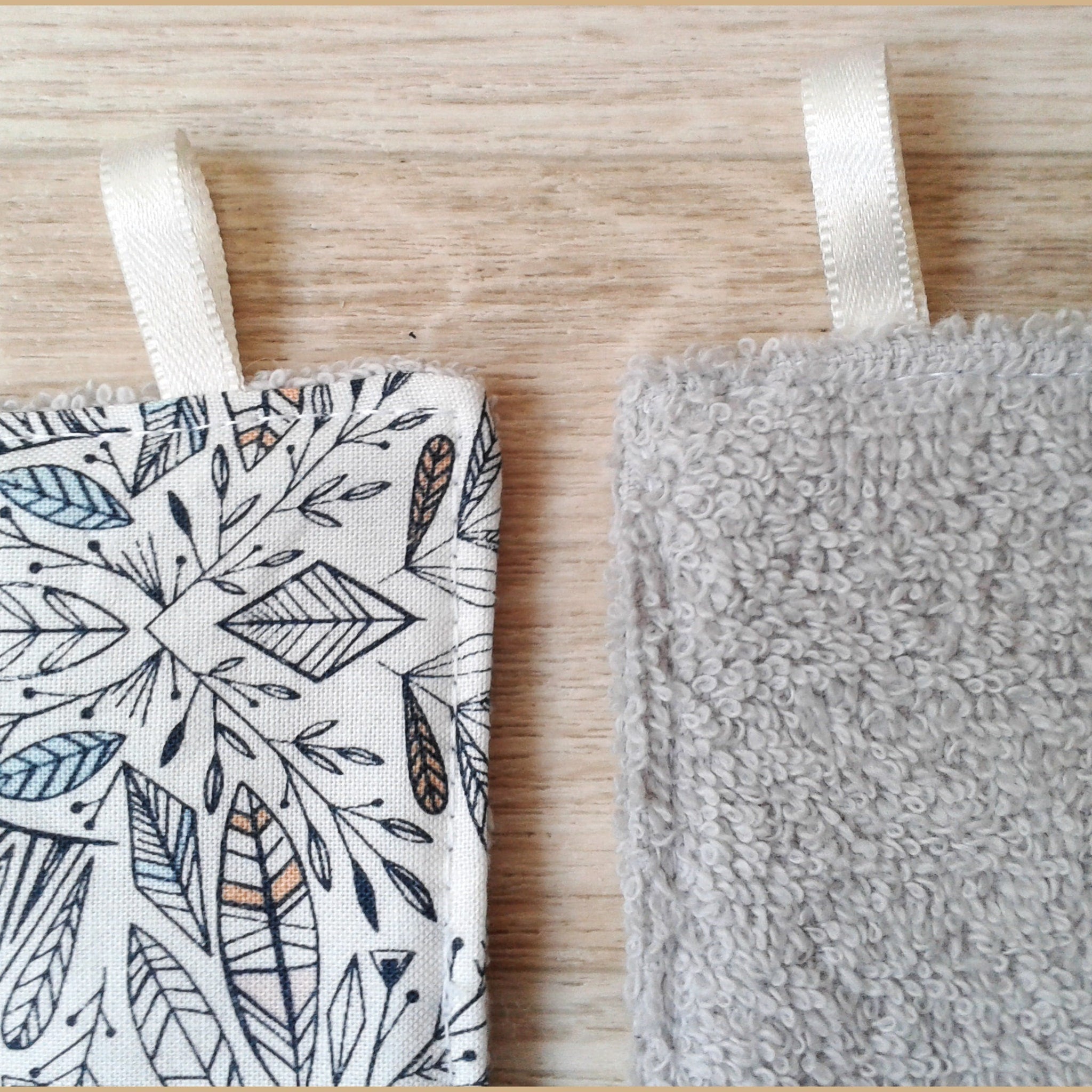 Washcloths with white, patterned fabric and gray terry cloth, with white ribbon loops