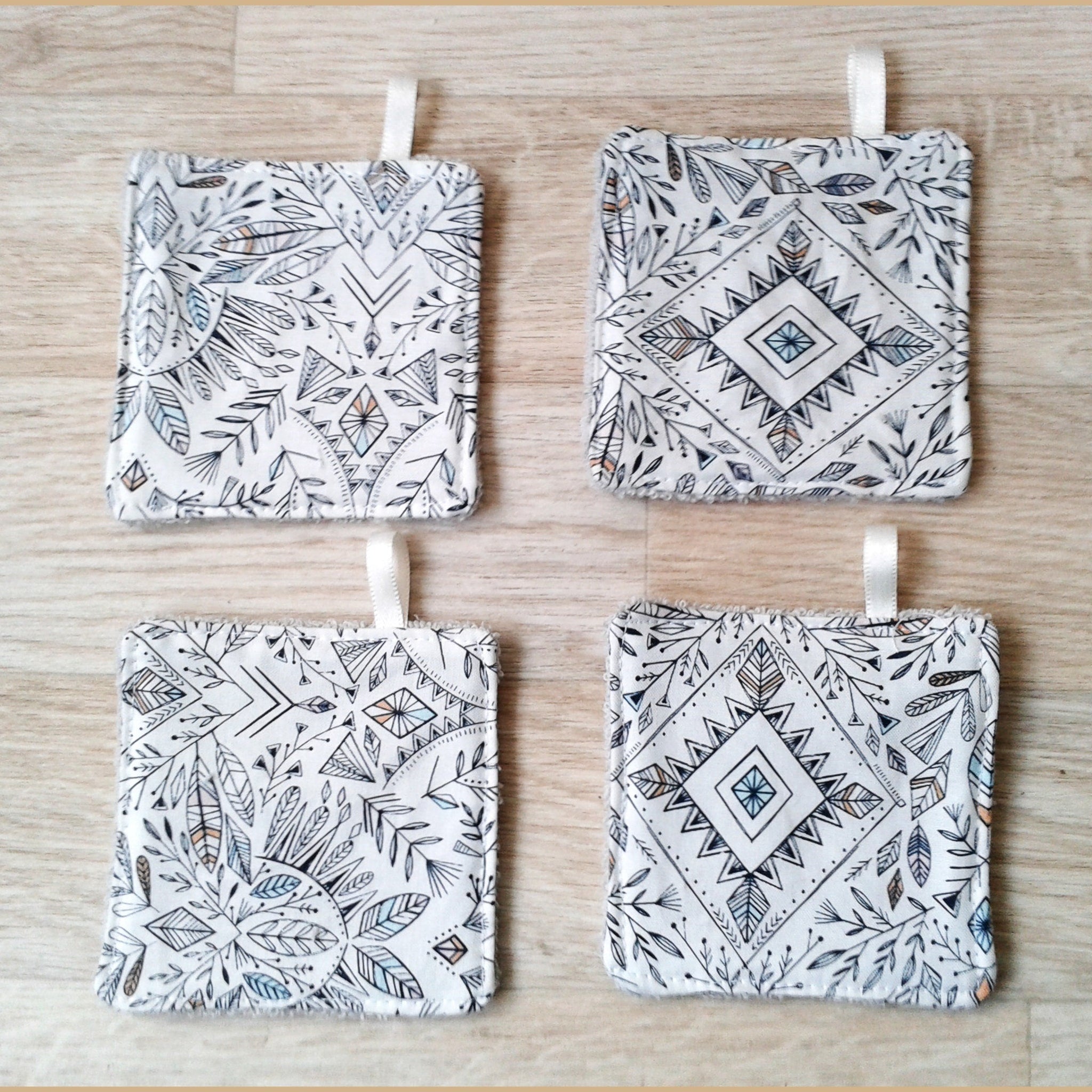 Coasters with white and black geometric pattern, with ribbon loop, on wood surface