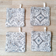 Coasters with white and black geometric pattern, with ribbon loop, on wood surface