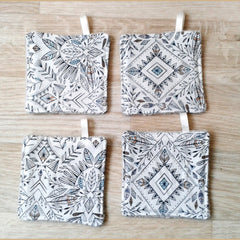 Coasters with white fabric, black and blue tribal pattern, and a loop for hanging
