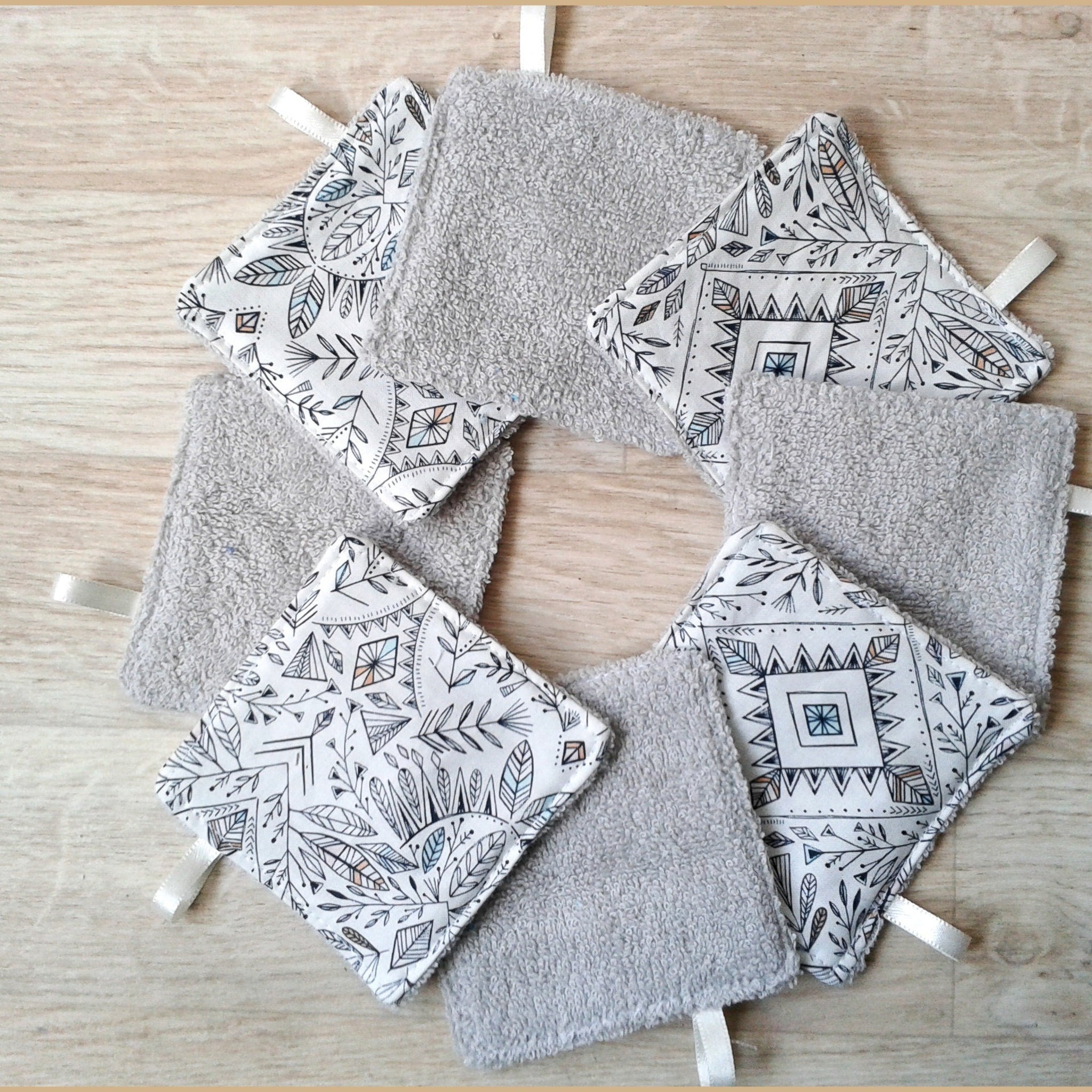 Baby washcloths with gray terry cloth, patterned fabric, and white ribbon ties arranged in a circle