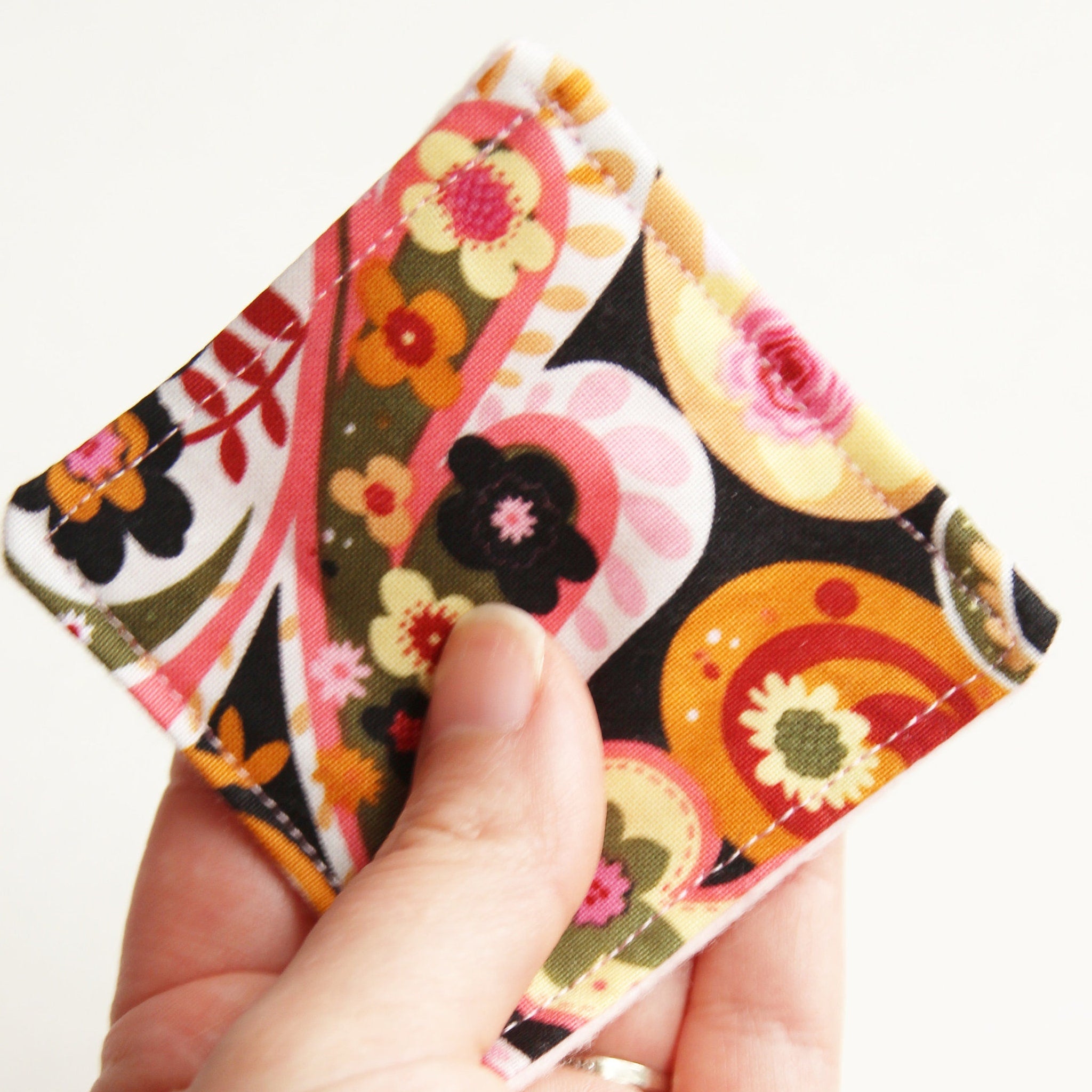 Floral print fabric square with pink, orange, and black pattern, held in hand