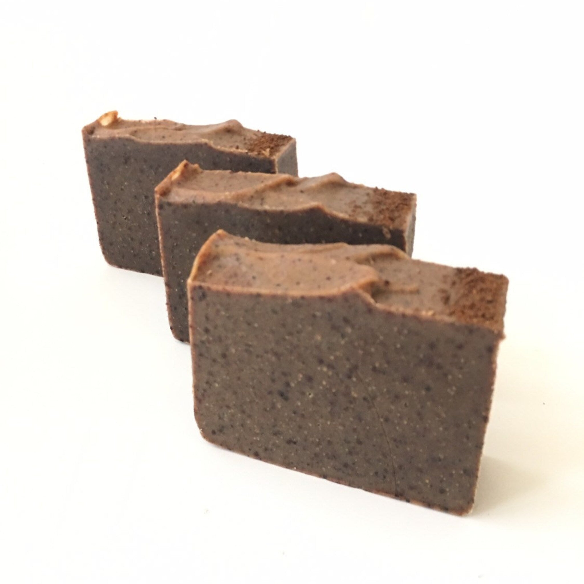 Soap bars, brown textured soap with rough edges, arranged in a row on white background