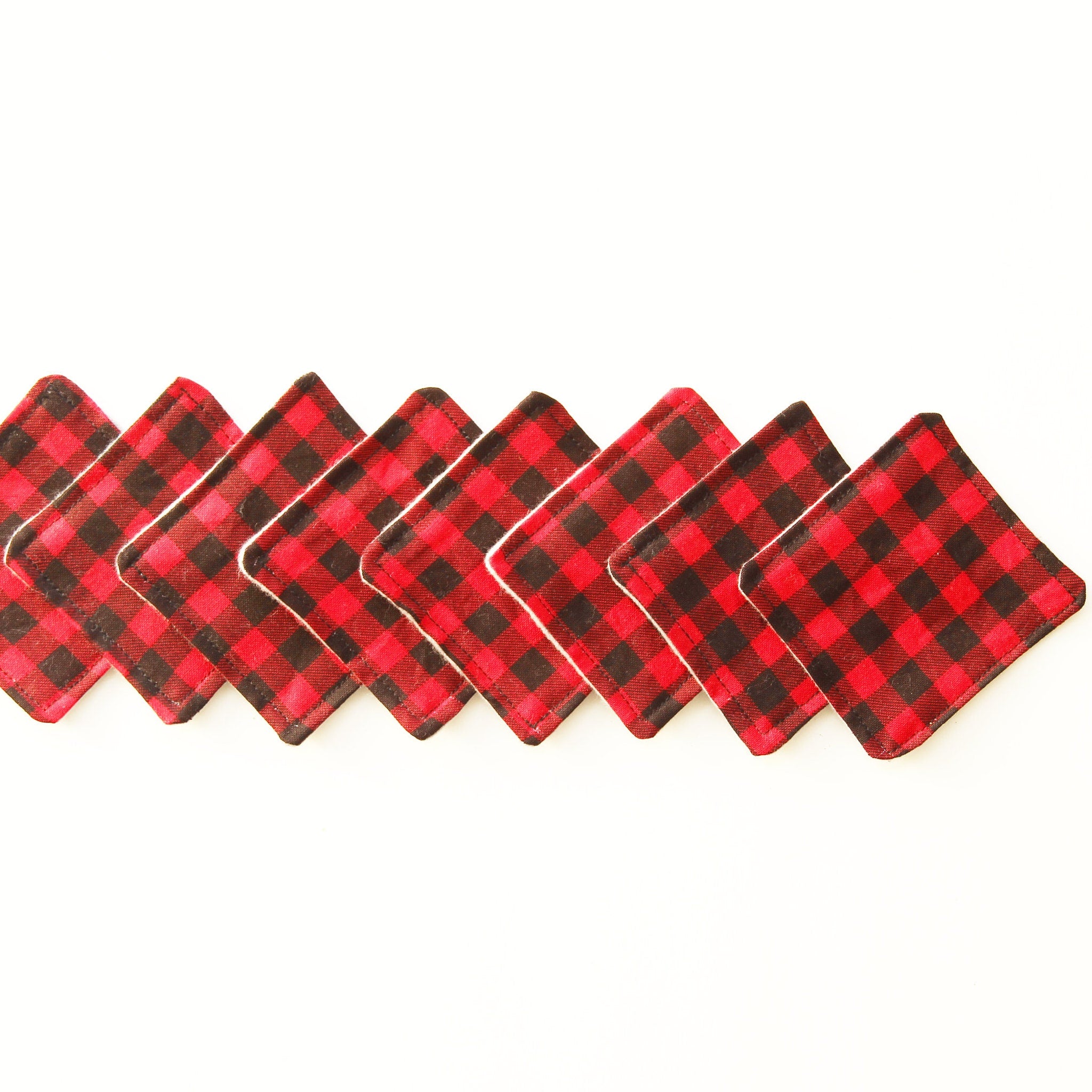 Red and black plaid fabric coasters with white stitching, arranged in a row