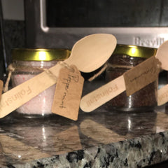 Lip scrub jars with gold lids, wooden spoons, and brown tags with text