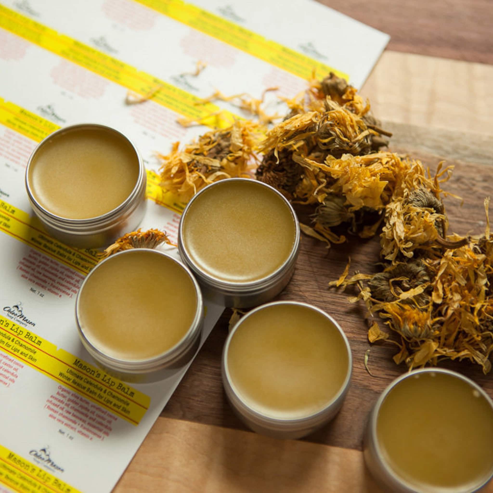 Lip balm tins with yellow balm, silver metal containers, and dried flowers on wood