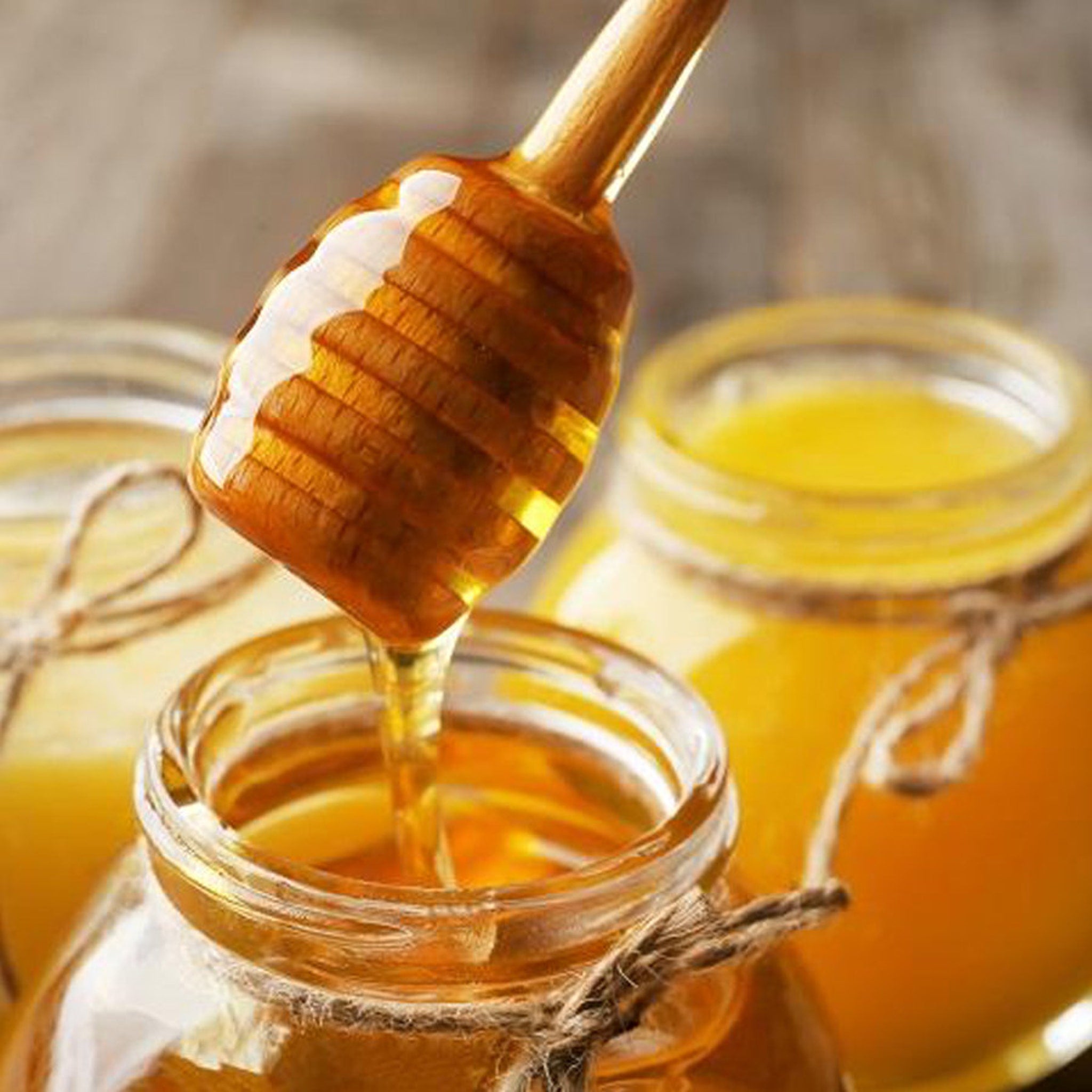 Honey dipper dripping honey into jar, wooden dipper, clear glass jar, natural twine wrap