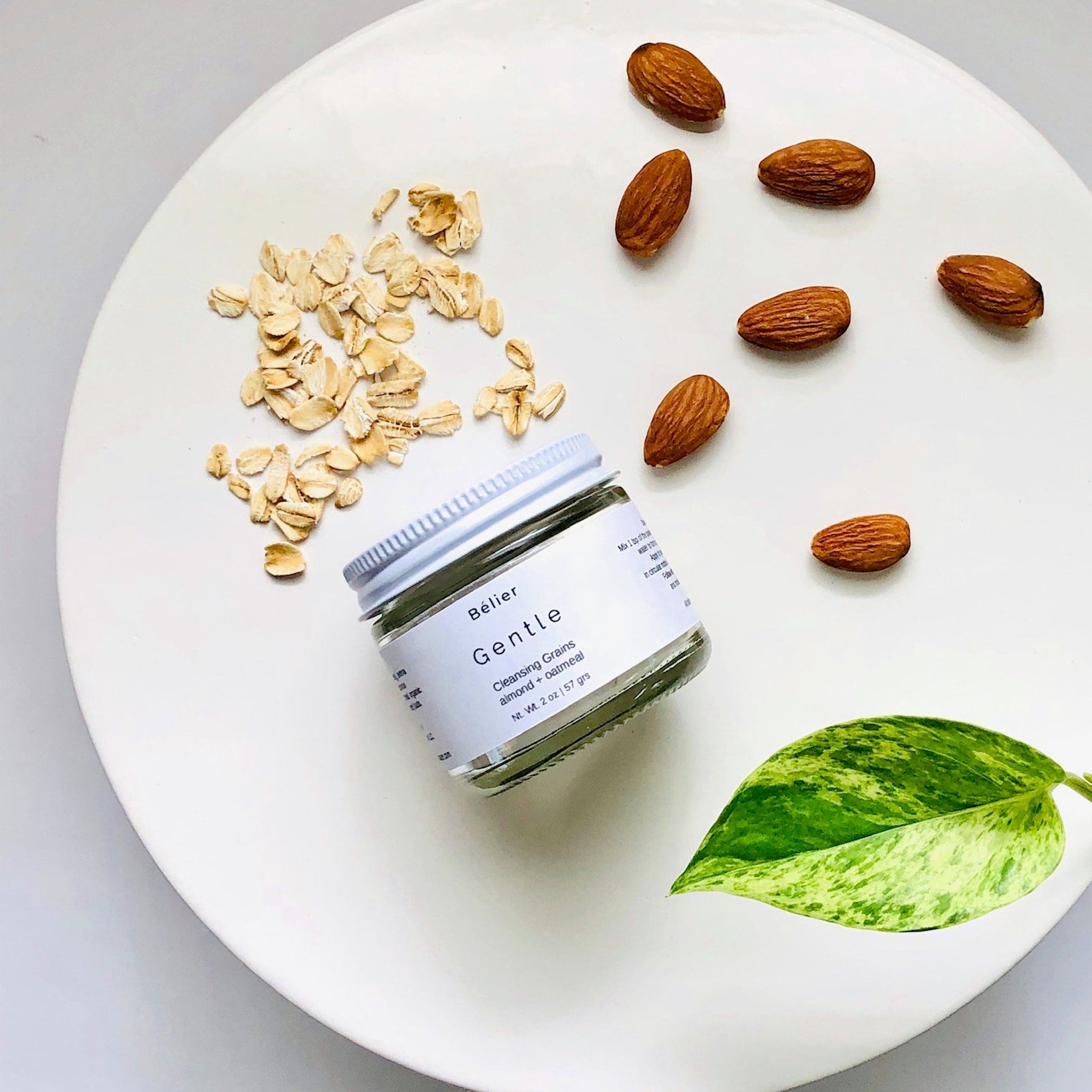 Cleansing grains jar with white label, brown almonds, and green leaf on white plate