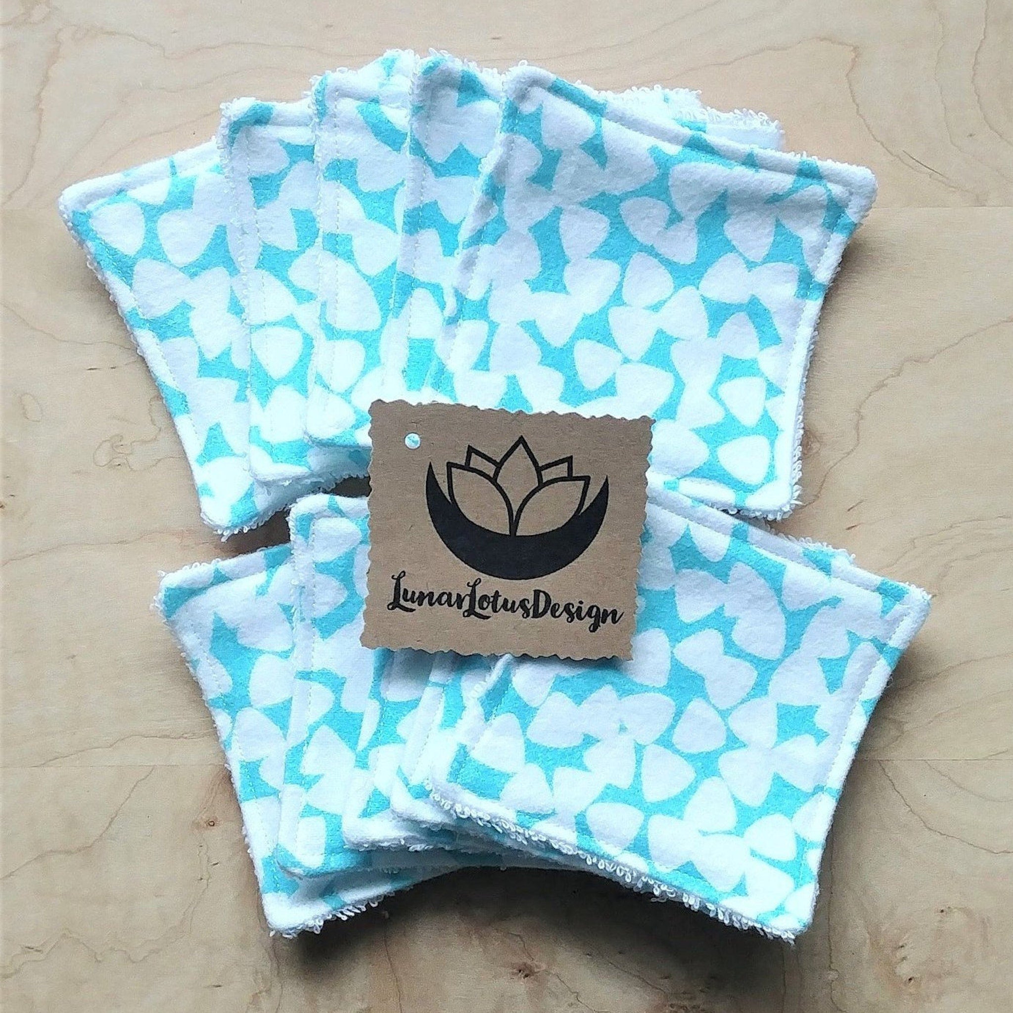 Reusable makeup remover pads, white and teal heart pattern, LunarLotusDesign tag on wooden surface