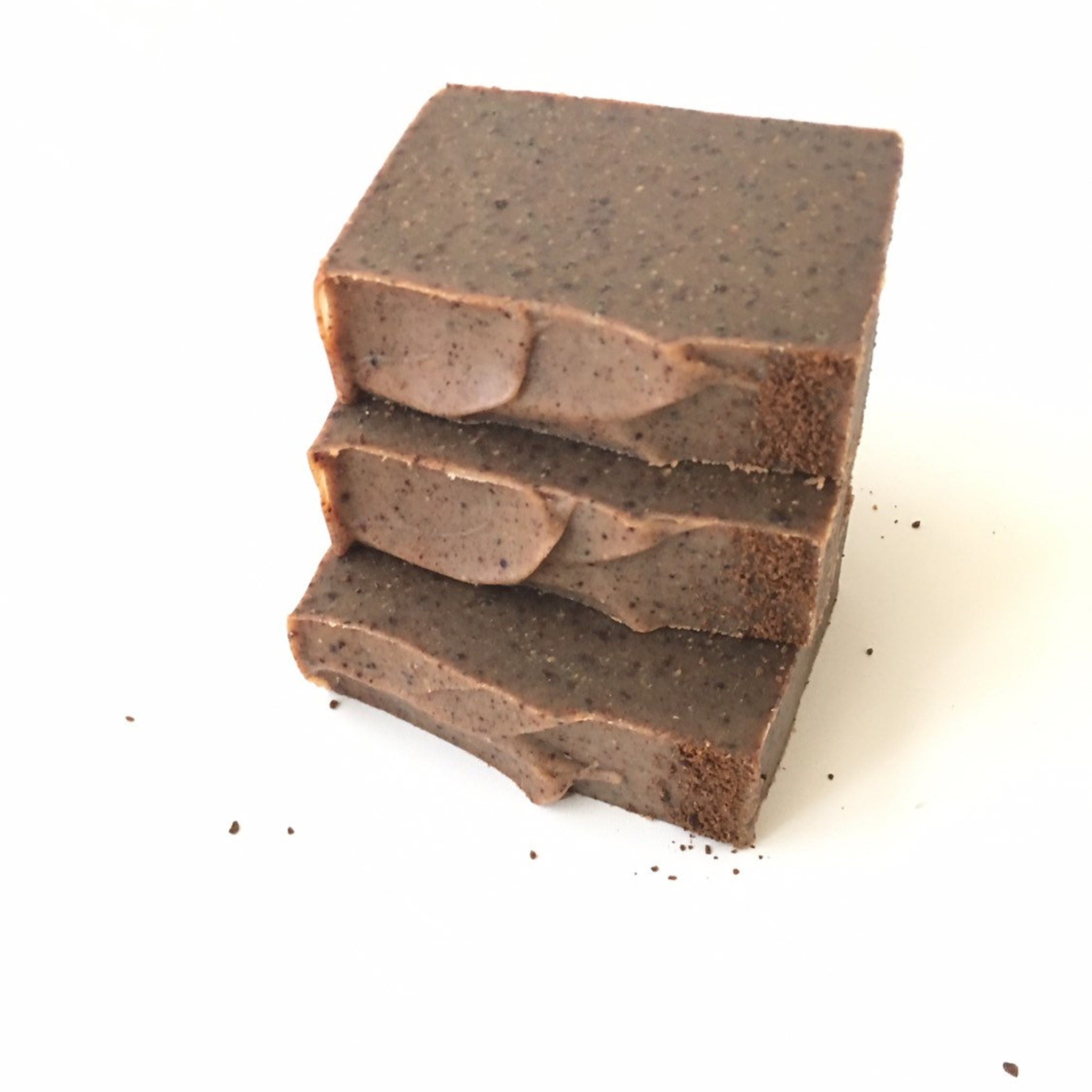 Soap bars stacked, brown color with speckled texture and rough edges, on white surface