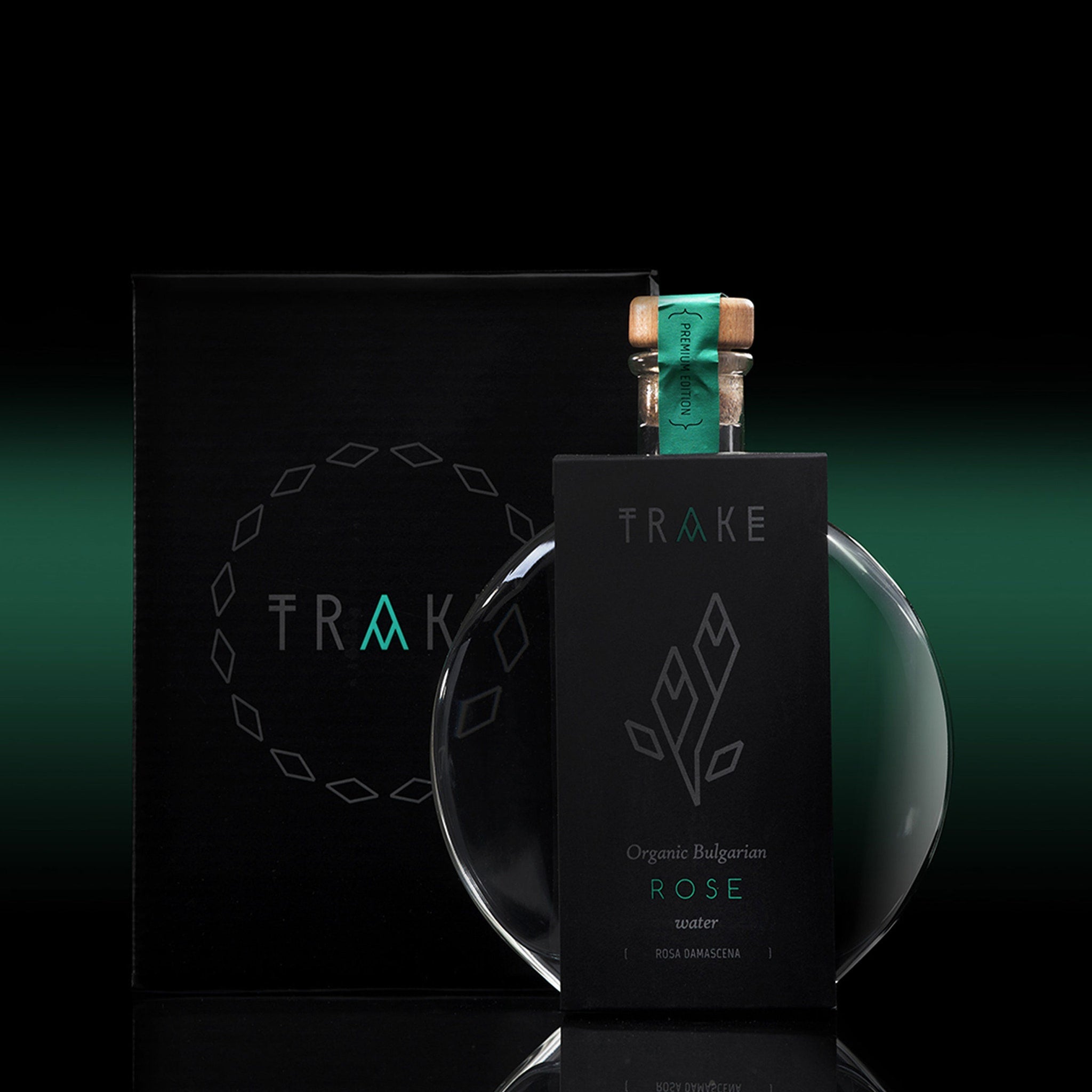 Rose water bottle with black label, clear glass, and TRAKE branding