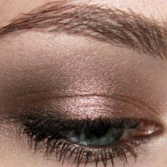 Hand applying hazelnut pearl mineral eyeshadow with a fluffy brush for a soft shimmer effect