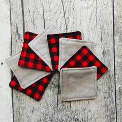 Coasters with red and black plaid pattern and gray fabric, stacked on wood surface