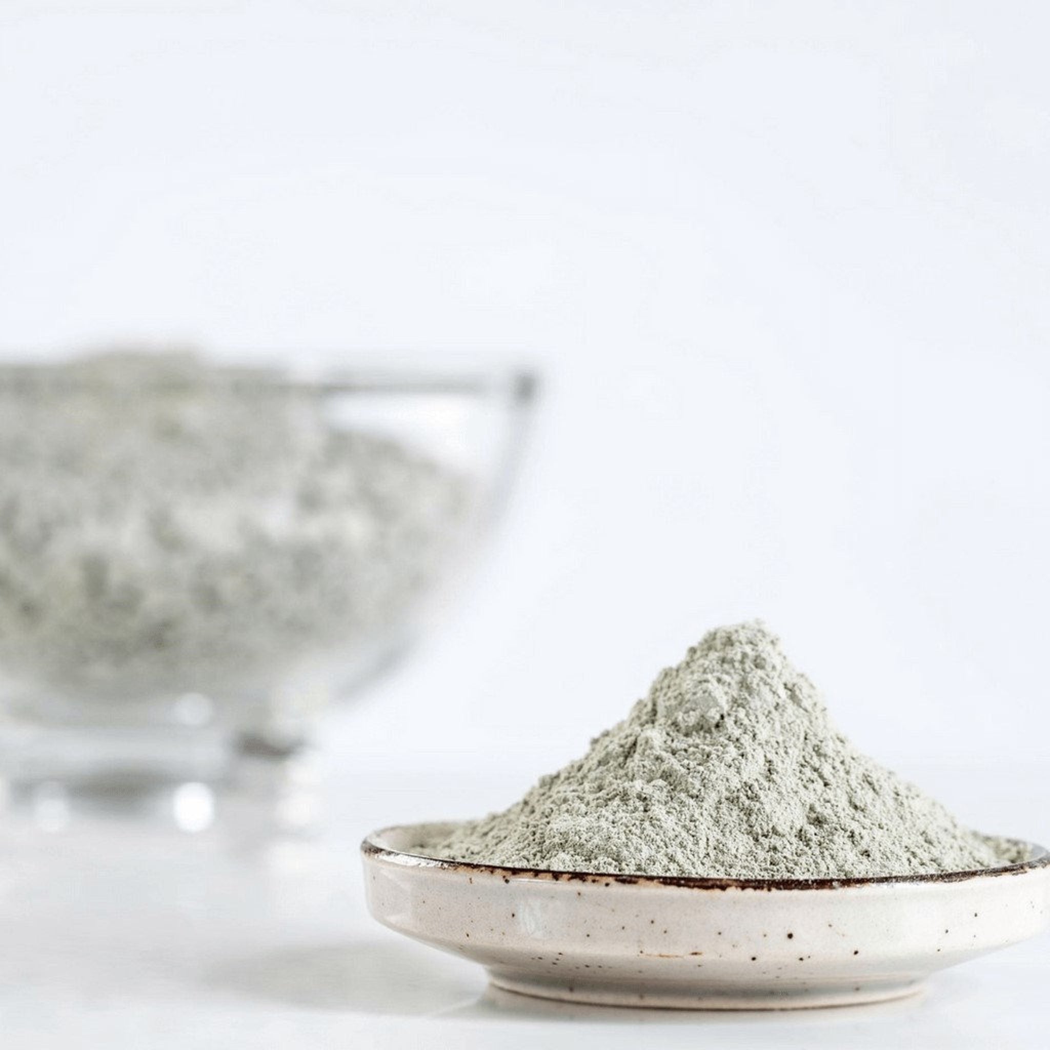 Clay powder in pale green, grainy texture, and small ceramic bowl