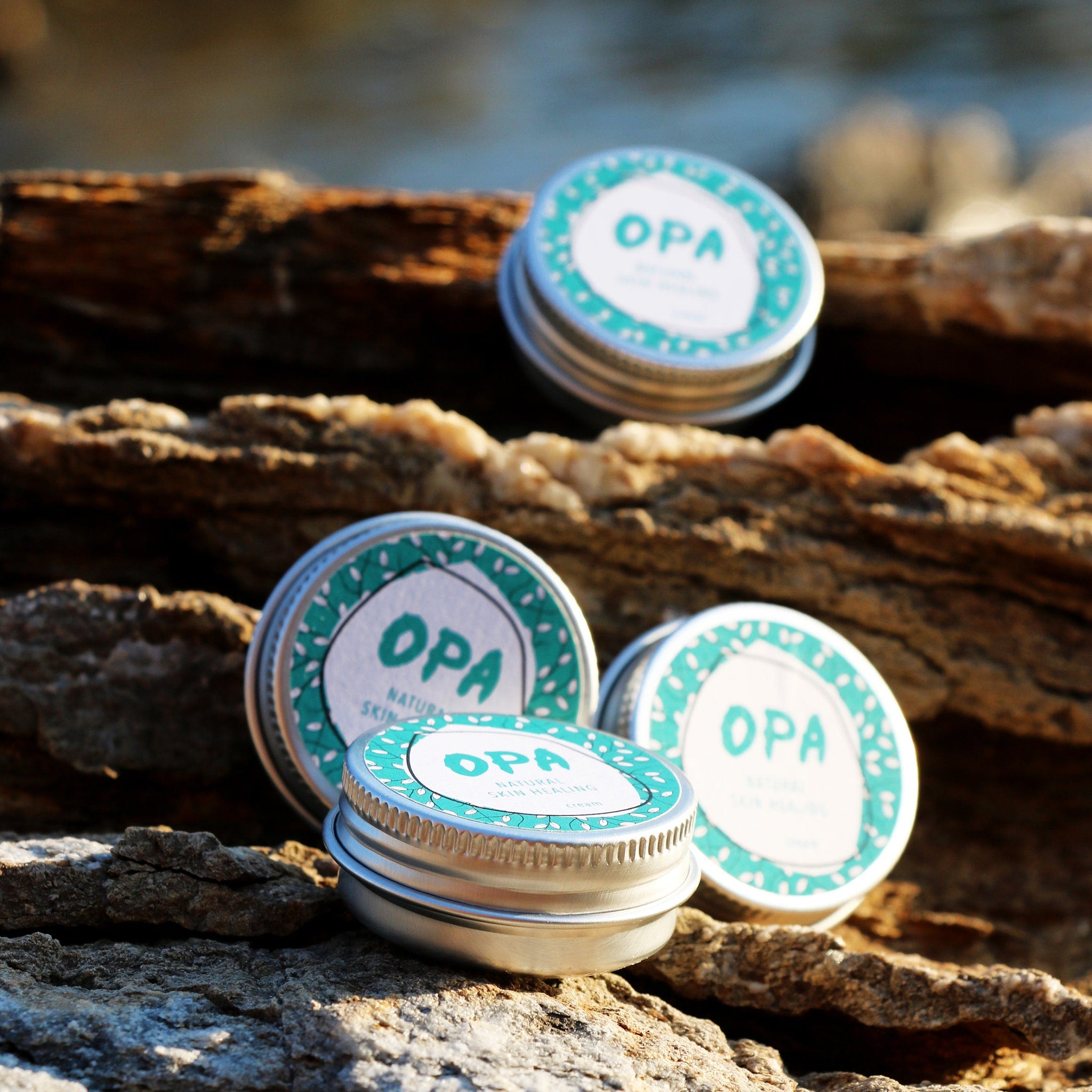Cream tins with teal and white labels, silver metal lids, and OPA text on wood background