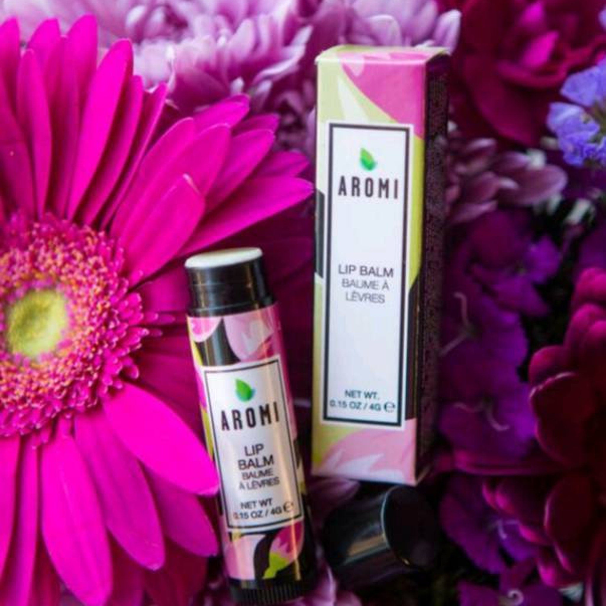 Lip balm tube with pink and black floral pattern, AROMI brand, next to matching box with text