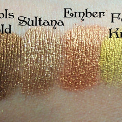 Side angle view of metallic copper orange eyeshadow pan catching light, showcasing rich shimmer texture