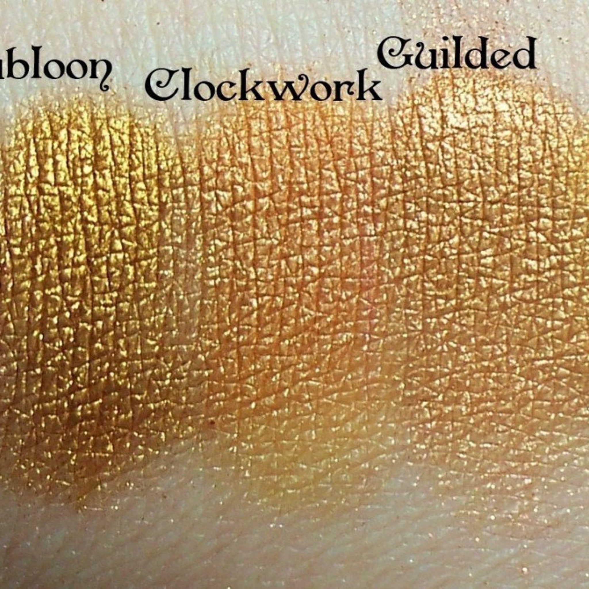 Side view of Gold Dubloon eyeshadow pan showing rich metallic finish and embossed logo details