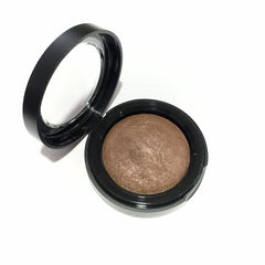Hand applying baked brindle brown eyeshadow with a fluffy brush, showcasing smooth pigment blend on eyelid.