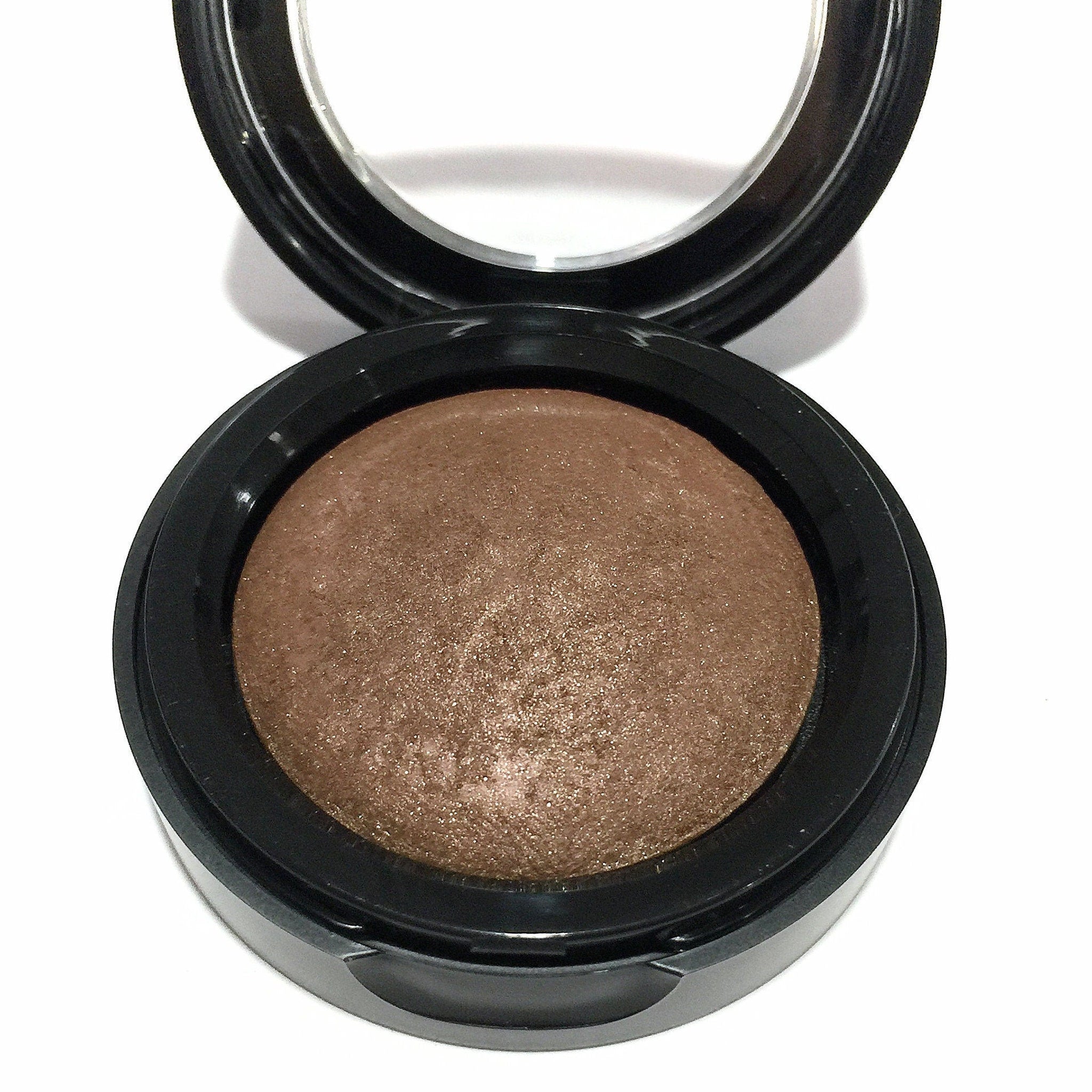 Close-up of baked eyeshadow pan showing rich brindle brown shade with subtle shimmer and smooth texture