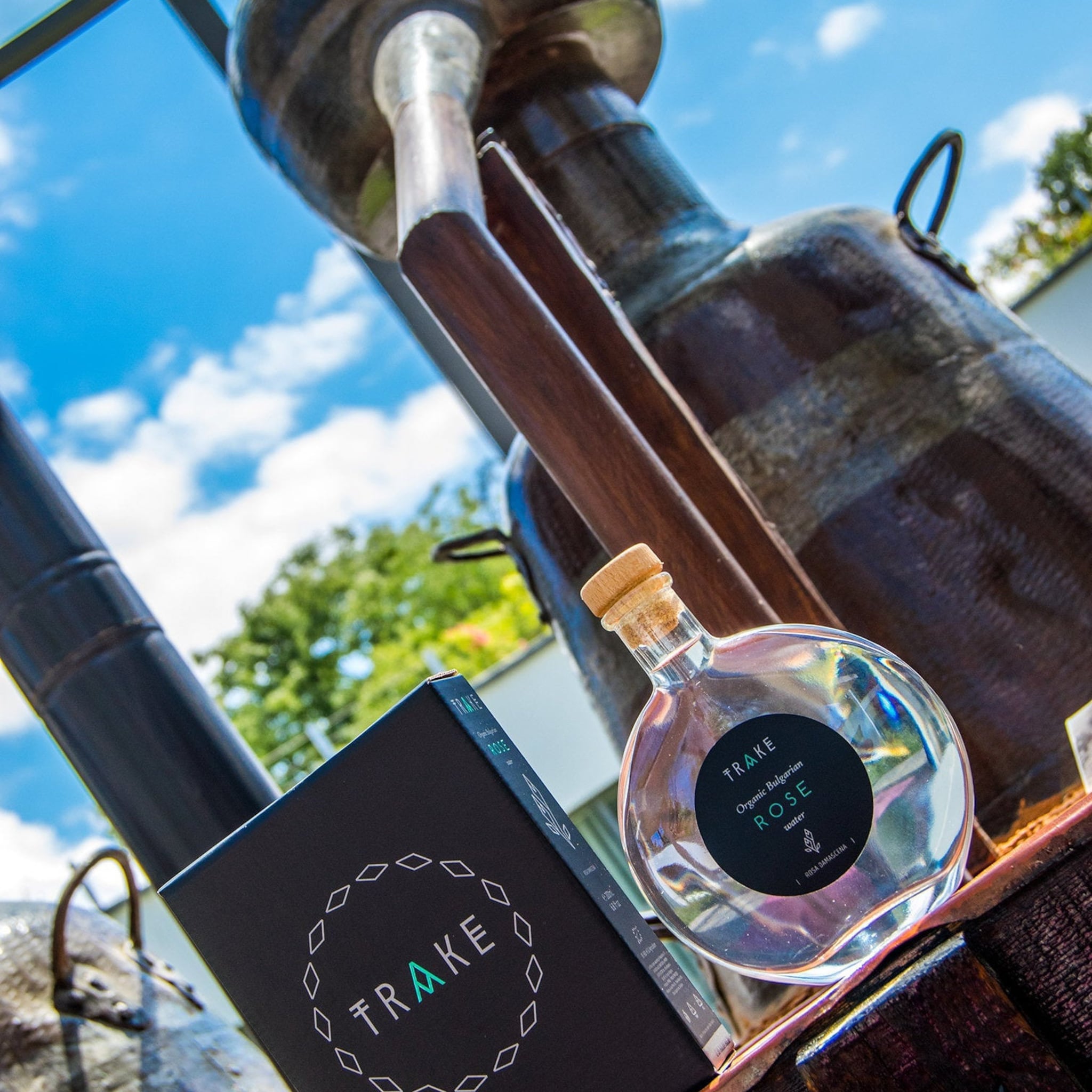 Rose water bottle with clear glass, wooden cork, and TRAKE label on black box