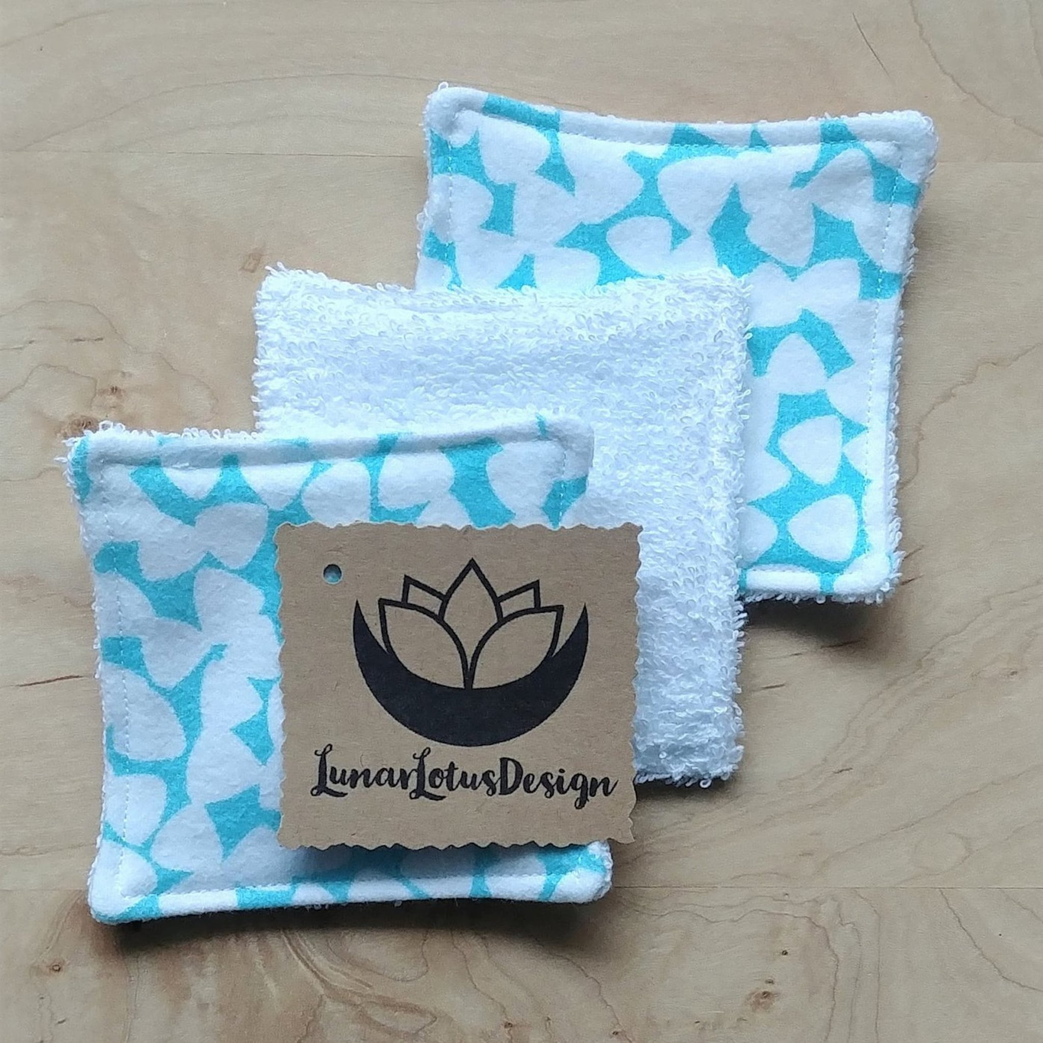 Reusable face cloths with white terry cloth, teal pattern, and Lunar Lotus Design tag.
